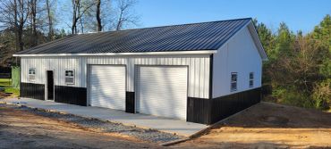Newly constructed metal garage with two white roll-up doors.