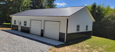 White and black garage building with three rolling doors.