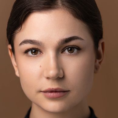 Close-up portrait of a young woman with brown eyes and neutral expression.