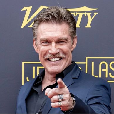 Man in navy suit smiling and pointing.