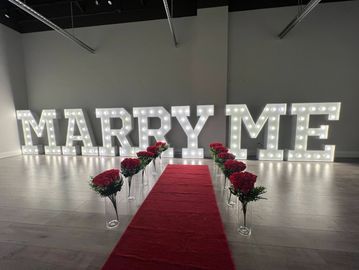 Marry Me marquee letters with a red carpet and rose decorations 