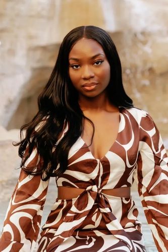 Woman in a brown and white patterned dress by Trevi fountain in Rome