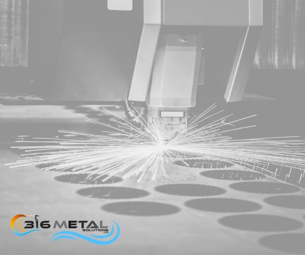 Laser cutting metal sheets with sparks flying at Big Metal Solutions.
