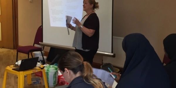 A woman gives a presentation to a small group in a casual setting.