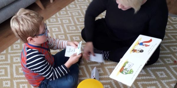 A child and an adult playing a card game on a patterned carpet.