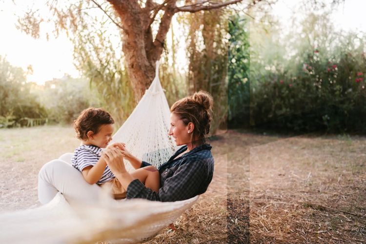 Mother and child enjoying time together on a hammock outdoors.