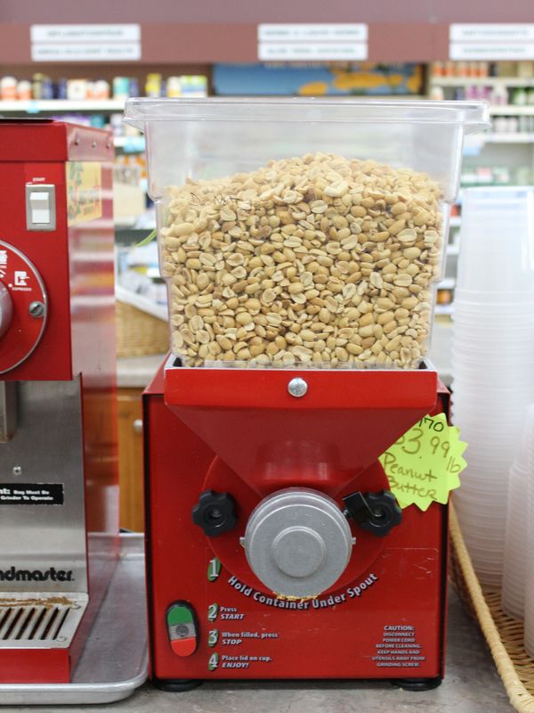 Peanut grinder machine filled with peanuts in a store.