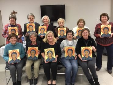 Group of women displaying hand-painted religious icons.
