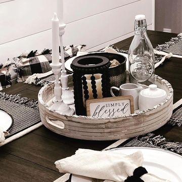 Farmhouse dining table with buffalo check placemats, centerpiece with candles and glass bottles. 