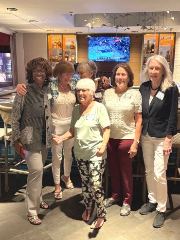 Group of women smiling and posing together indoors.
