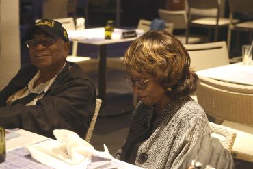 Two elderly individuals seated at a restaurant table engaged in quiet moments.