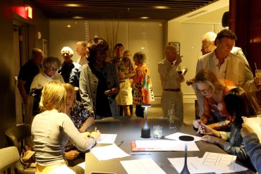 People socializing and working in a warmly lit room.