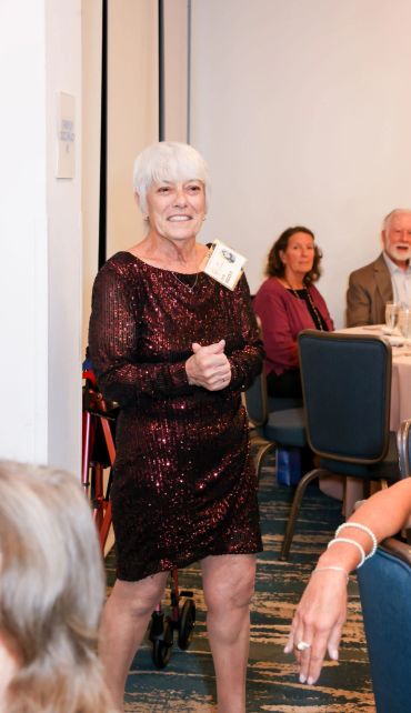Woman in a sparkly dress standing and smiling at a formal event.