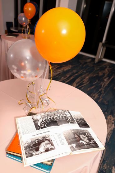 Open yearbook with balloons on a table at an indoor event.
