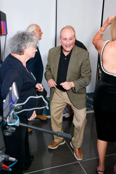 A group of older adults dancing and socializing at an indoor event.