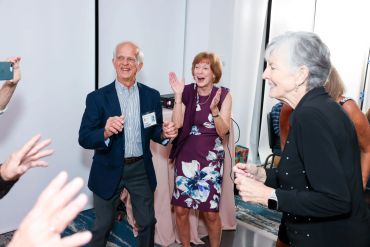 Elderly friends joyfully dancing at a social event.