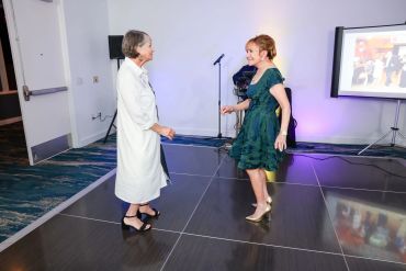 Two women dancing on a dance floor at an indoor event.
