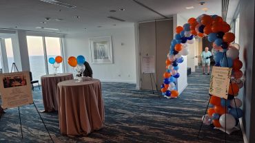 Decorated event space with balloon arch and tables for a gathering.