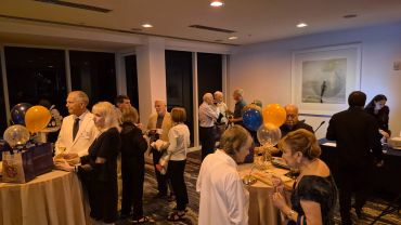 People socializing at an indoor event with balloons and refreshments.