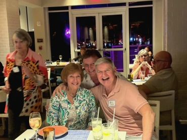 Three people smiling at a dinner table in a restaurant.