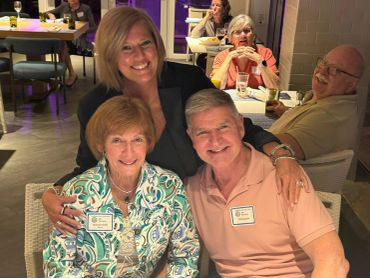 Three people smiling and posing together at a social event.