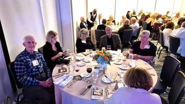 A group of people sitting around a dining table at a formal event.