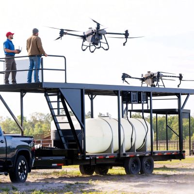 Two men operating large drones launched from truck trailer platform.