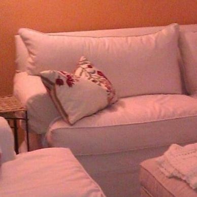 Cozy living room with white sofas and decorative pillows under warm lighting.