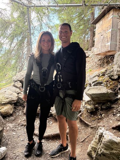 Couple wearing climbing harnesses in rocky area.