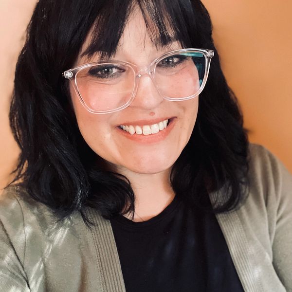 Smiling woman with glasses and dark hair.