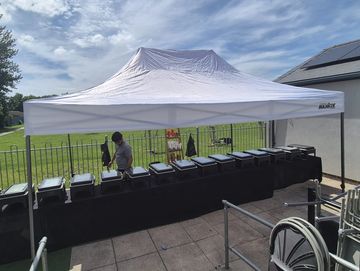 Outdoor buffet setup under a white canopy tent.