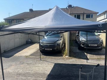 Two SUVs parked under a canopy between houses.
