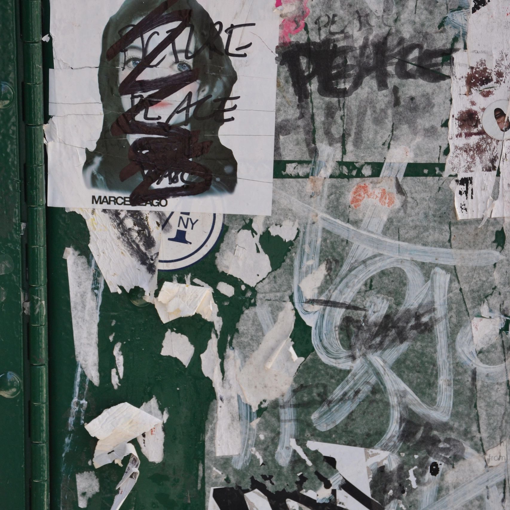 Worn green surface covered in torn posters and graffiti.