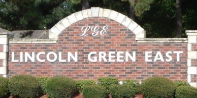 Sign reading Lincoln Green East on a brick wall.