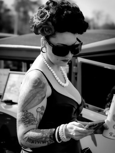 Black and white photo sunglasses looking at phone.