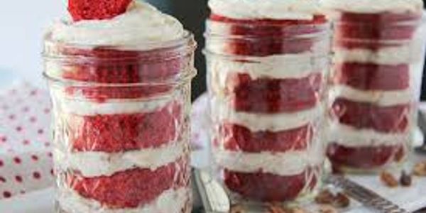 Layered red velvet cake with cream cheese frosting in glass jars.