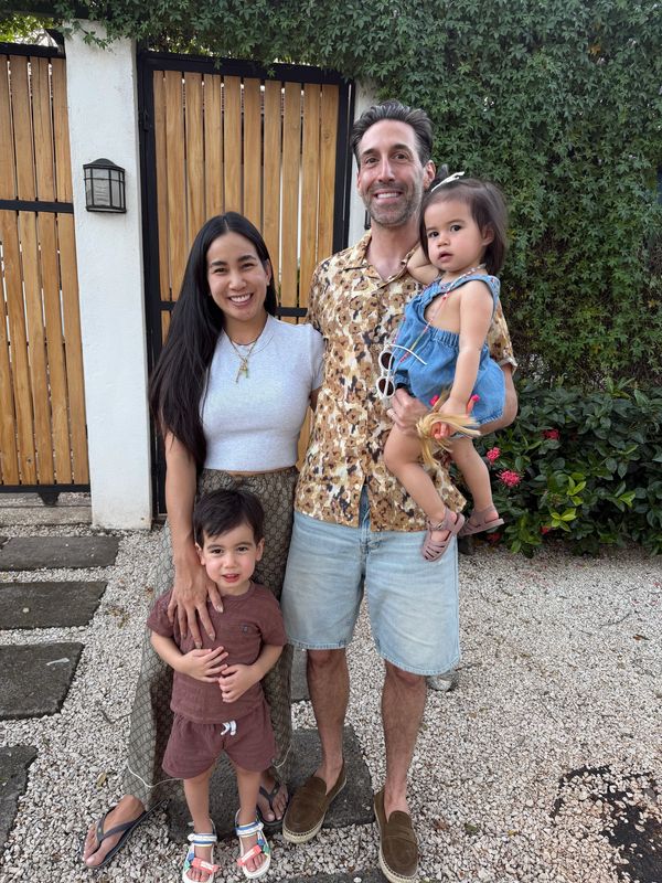 Happy family posing outdoors by a wooden gate.