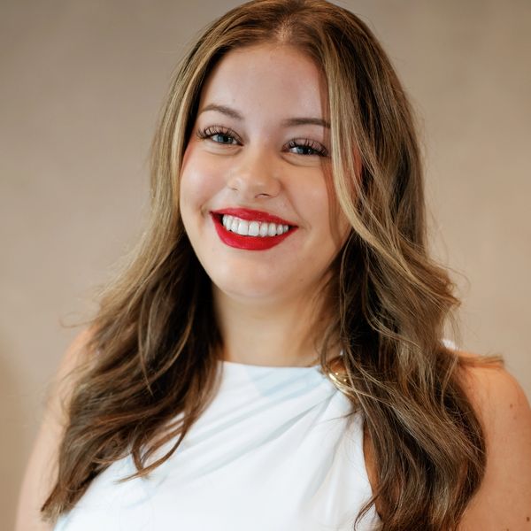 Woman with long hair and bright red lipstick smiling.