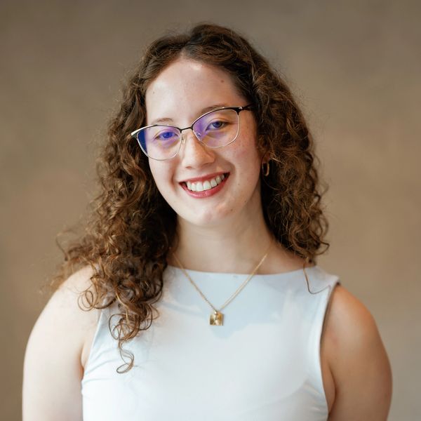 Smiling woman with curly hair and glasses.