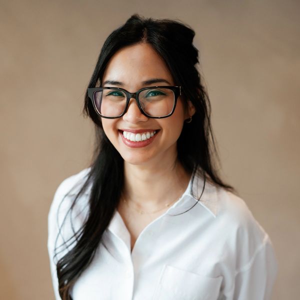 Smiling woman with glasses and long black hair.