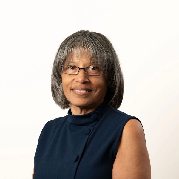 Smiling woman with glasses in a navy sleeveless top.