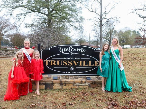 Five girls in formal dresses pose by a welcome sign in Trussville.