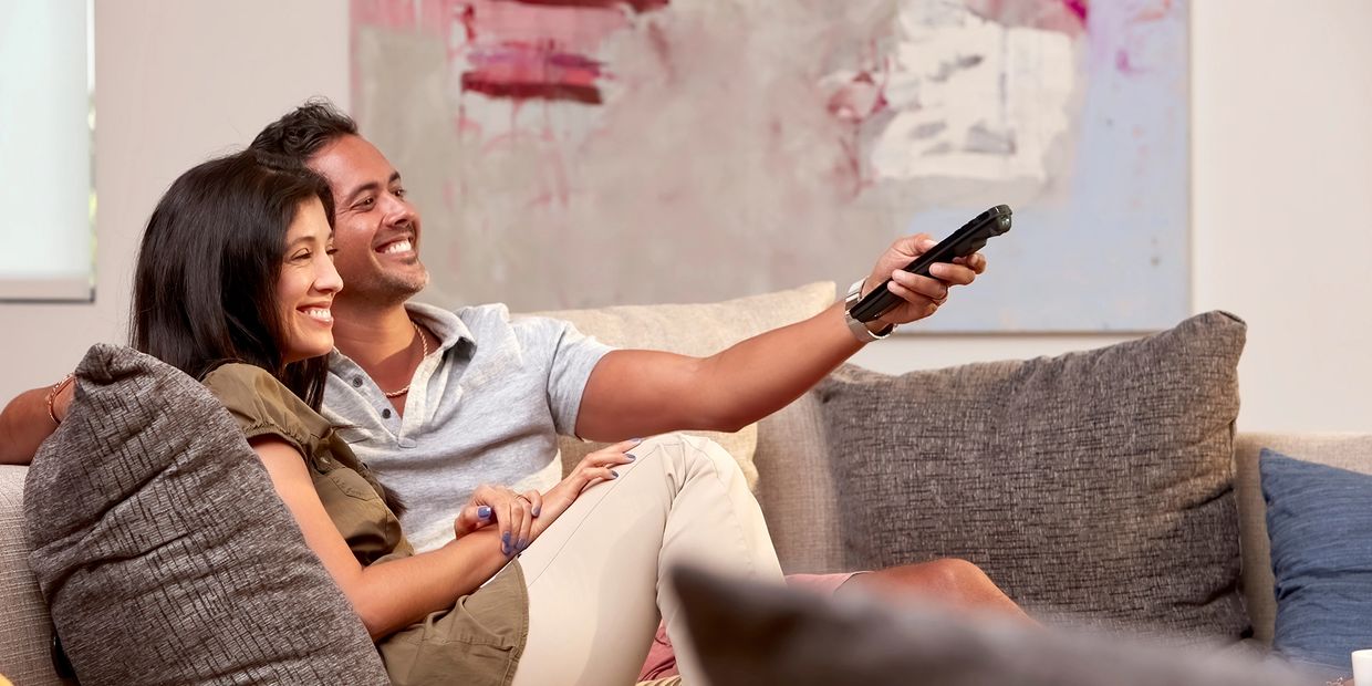 Happy couple watching TV on a couch.