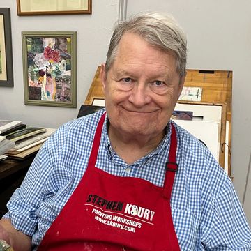 Smiling man in a red apron in an art studio.