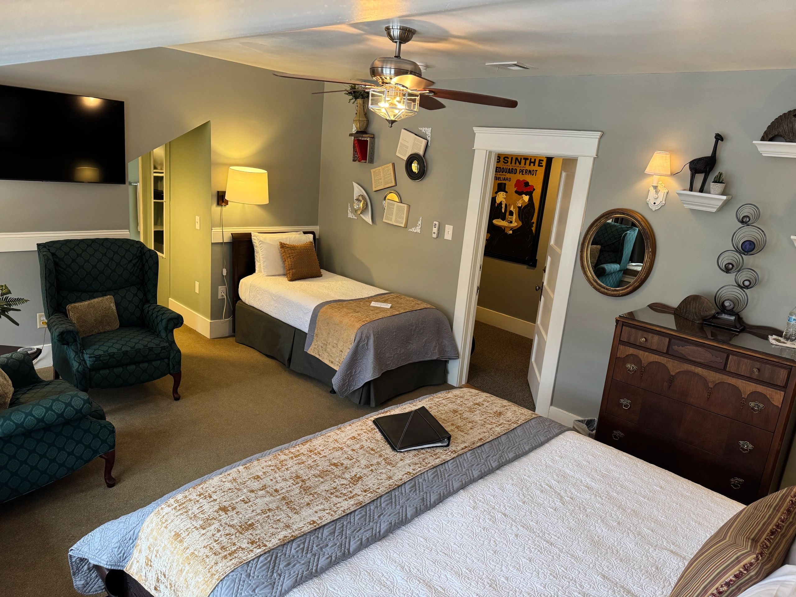 A wide view of a hotel room with two beds, a dresser, armchair, and TV