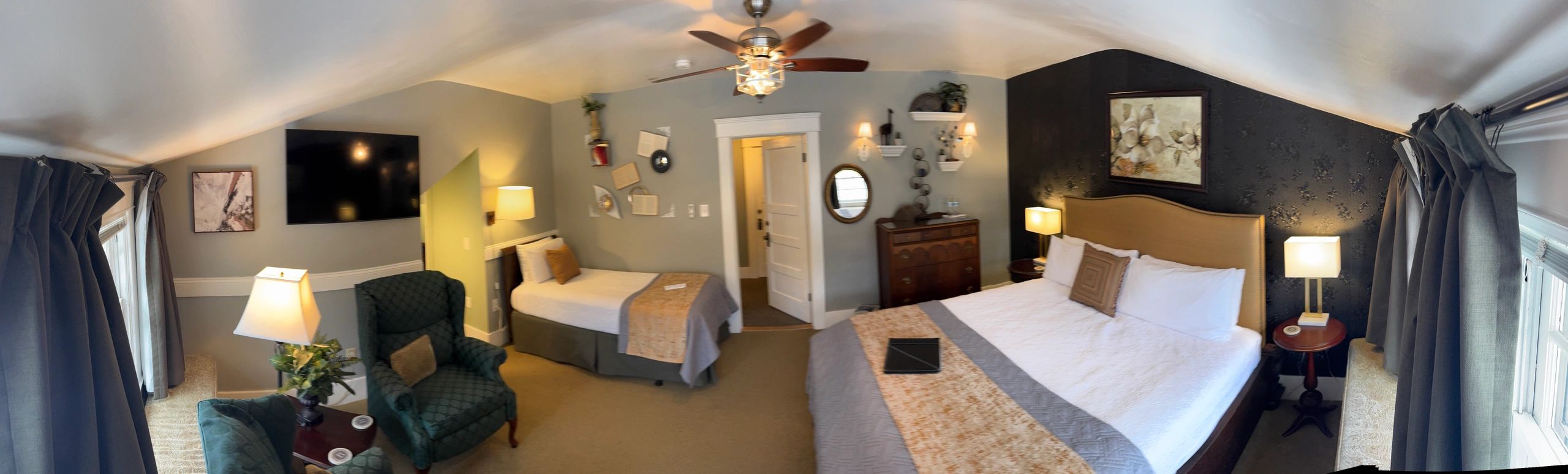 A wide-angle view of a hotel room with two beds, a desk, and various decorative items.