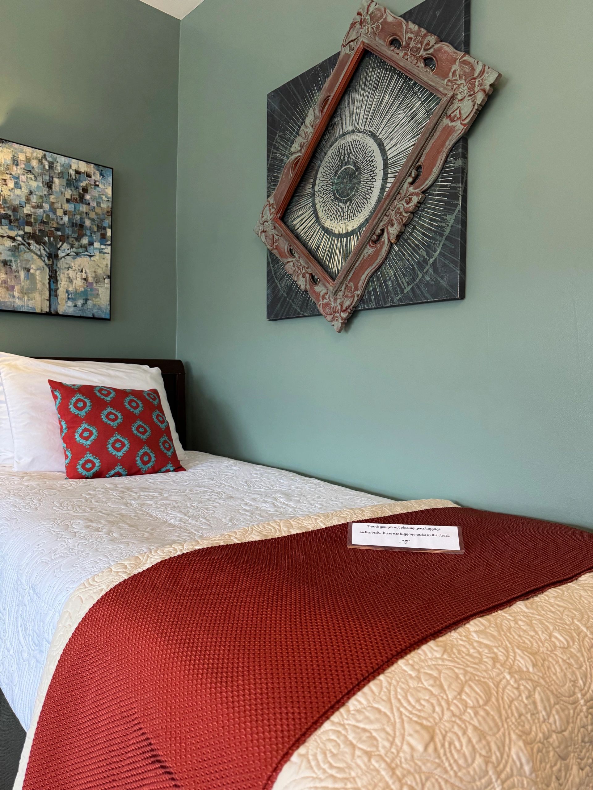 a bed with a white comforter, red blanket, and two pillows