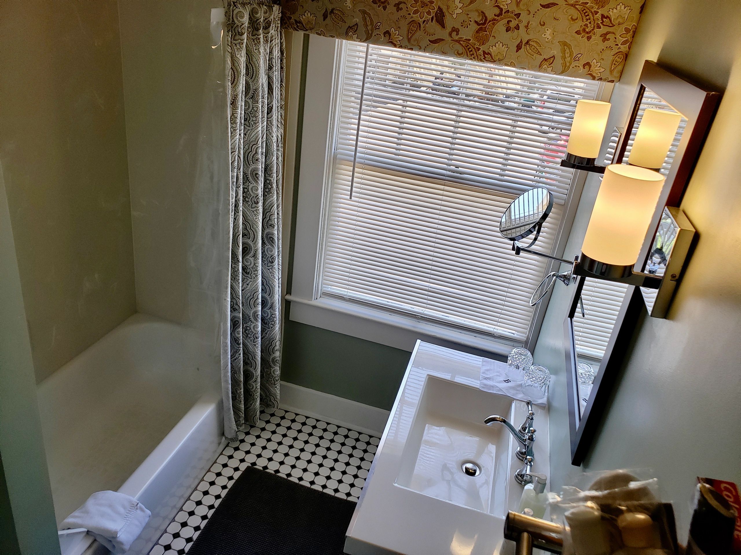 A bathroom with a shower, tub, sink, and mirror