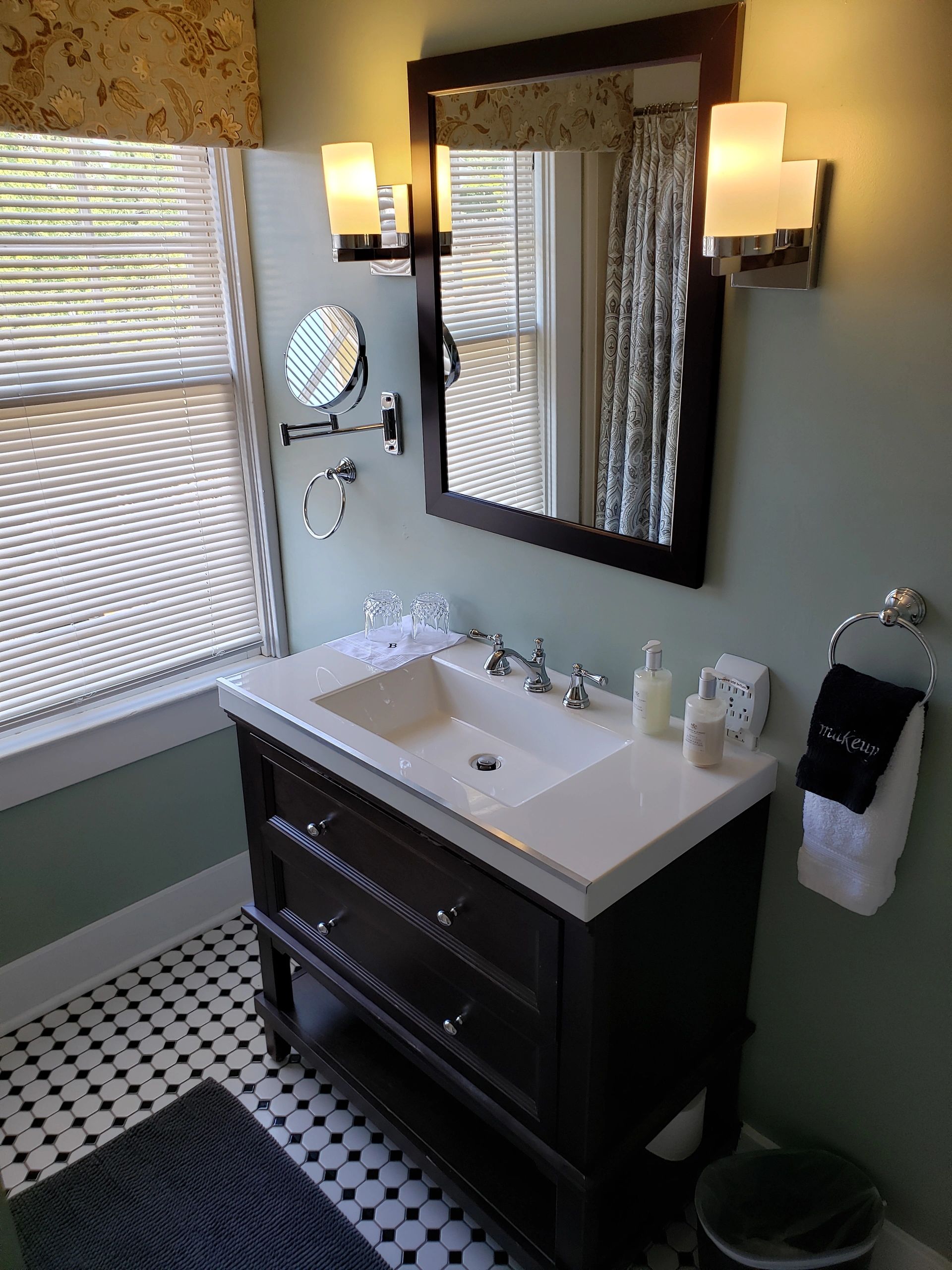 A bathroom vanity with a white sink, dark wood drawers, and a mirror with lights on either side.