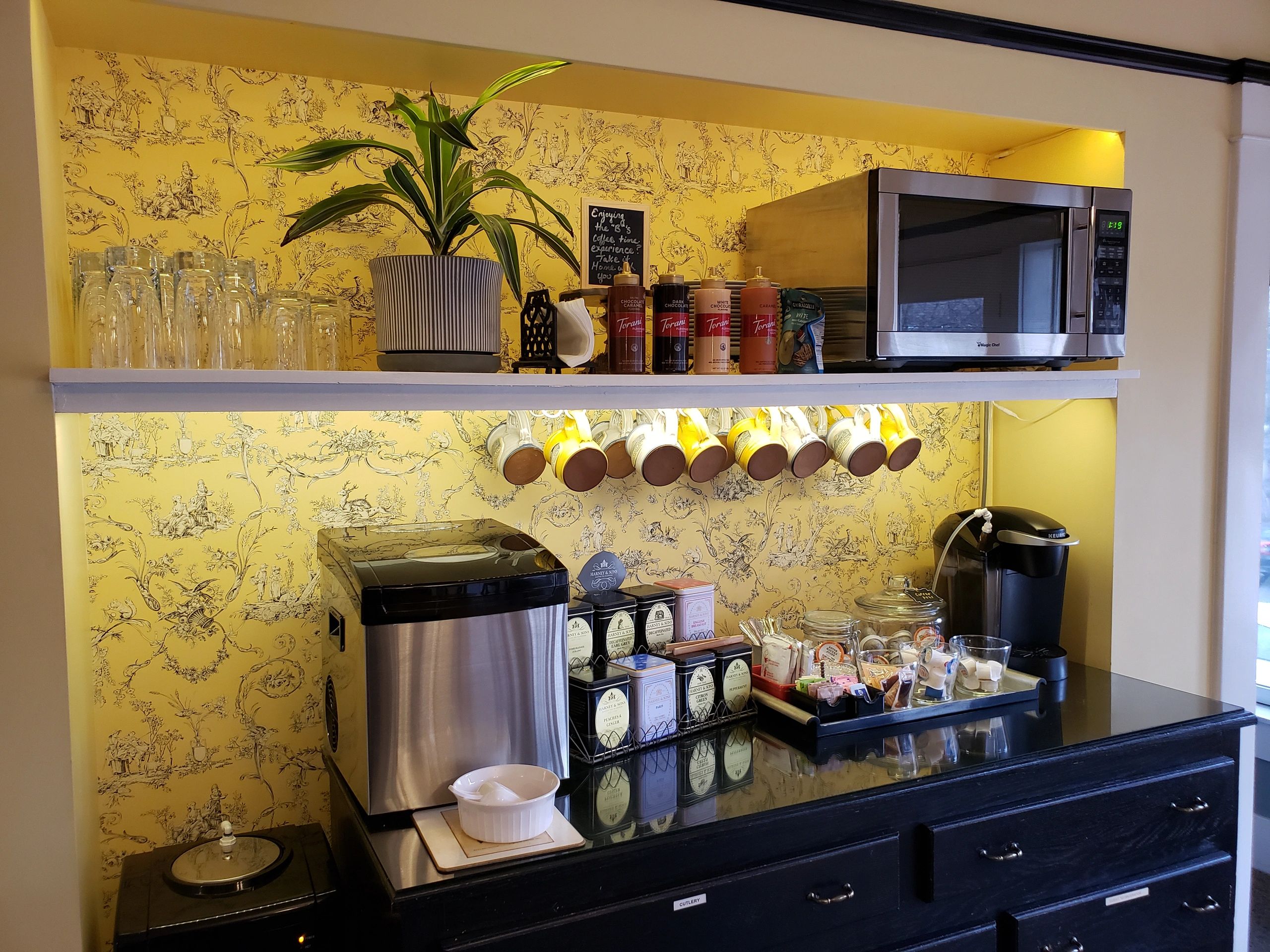 a hotel breakfast bar with a coffee maker, microwave, and tea